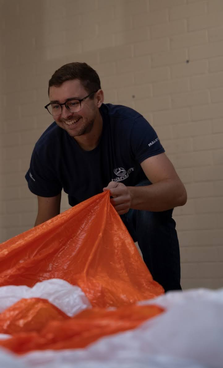 BHPA-certified instructor at Sky Riders professionally repacking a paraglider reserve parachute in a climate-controlled Somerset workshop.